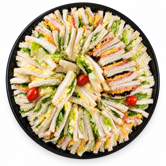 Assorted sliced sandwich platter with layered lettuce, tomatoes, and ham slices