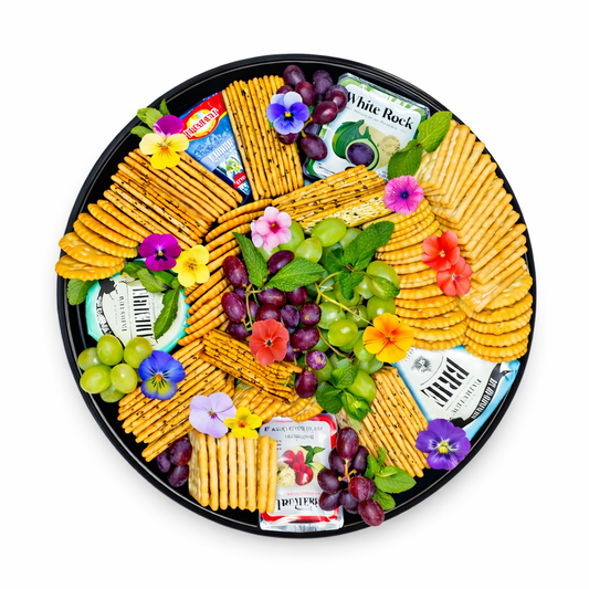Cheese platter with crackers, grapes, herbs, and cheese wedges